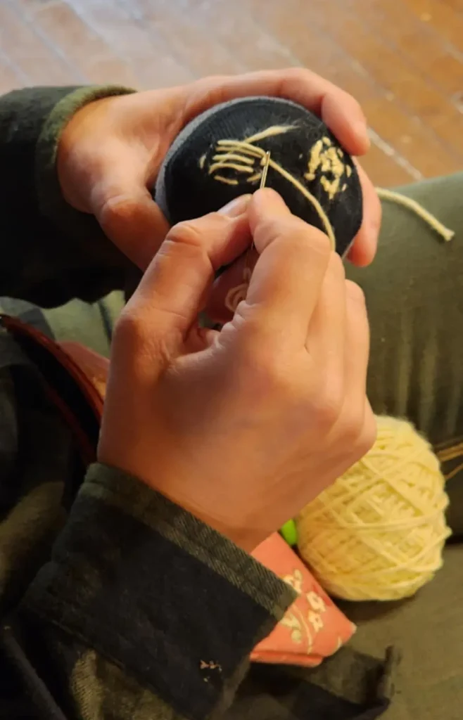 Close up of hands holding a ball and demonstrating darning.
